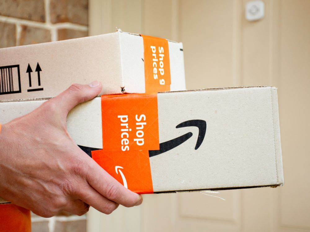 A person holds a package delivery from Amazon