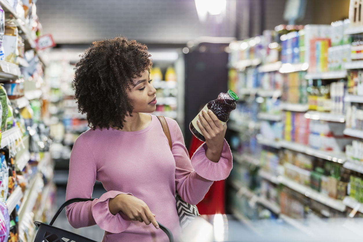 A woman reads a food label while shopping at the grocery store