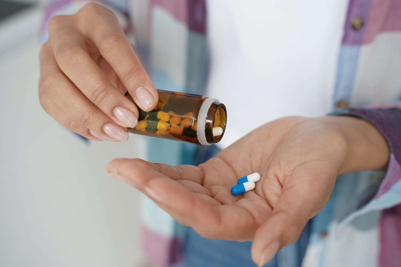 Woman pouring pills out of medication bottle