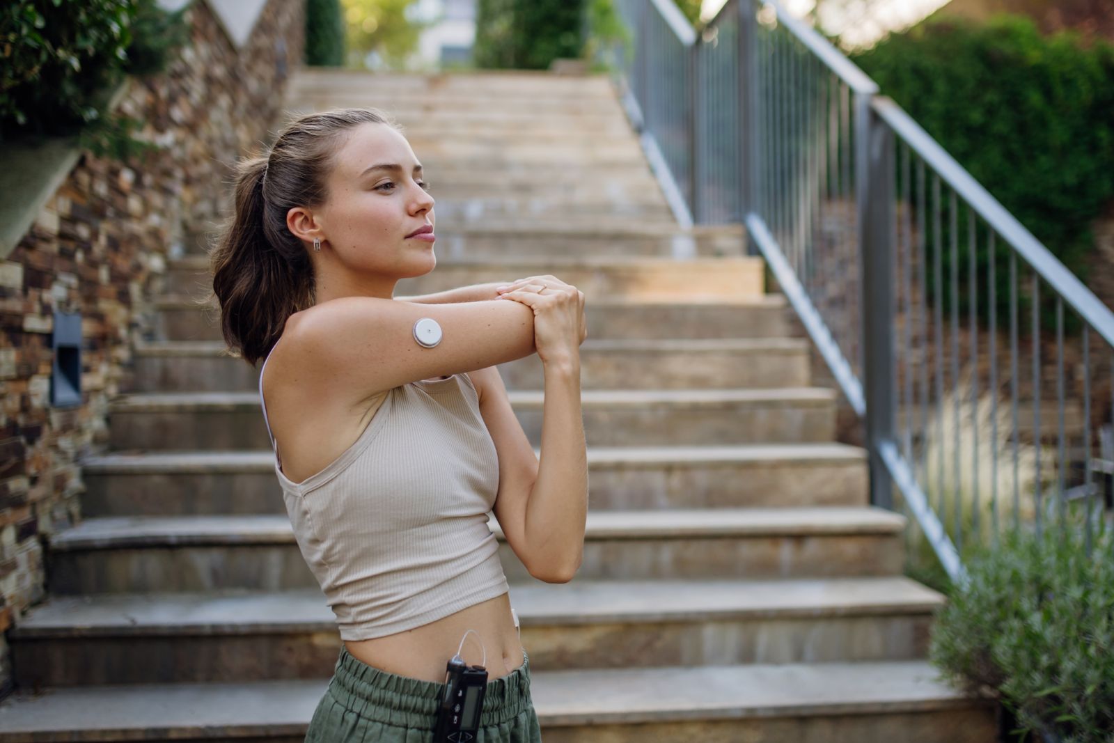 A woman with diabetes wears a CGM and stretches before exercising