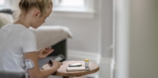 girl using insulin pump checks blood sugar