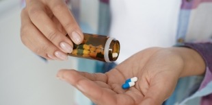 Woman pouring pills out of medication bottle