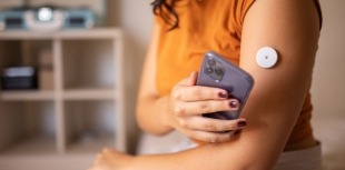 A person with diabetes uses a CGM to check her blood sugar