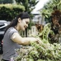 A woman examines flowers while wearing a CGM