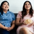 Women with obesity enjoy some popcorn while watching a movie