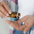 Woman pouring pills out of medication bottle